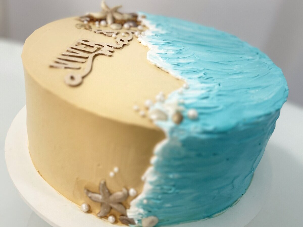 Bolo de aniversário tema praia em tons bege e azul com estrelas-do-mar decorativas